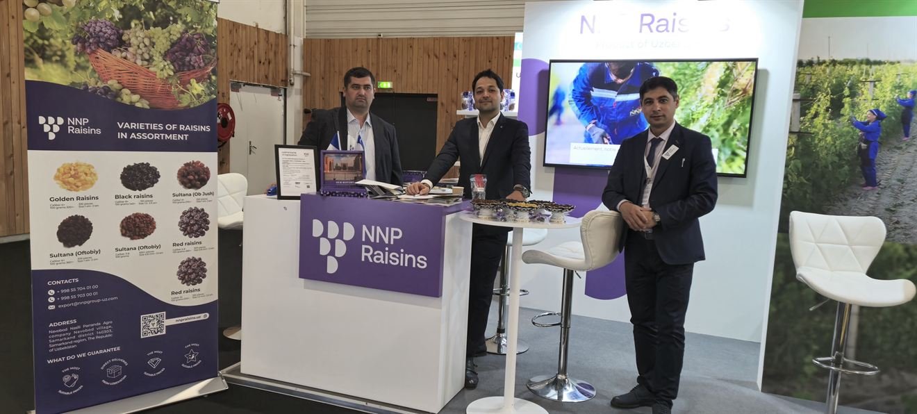 The NNP Raisins stand at SIAL Paris 2024 seen end to end: a roll-up banner listing the raisin varieties, three of the team at the counter, and a screen playing footage from the vineyards.