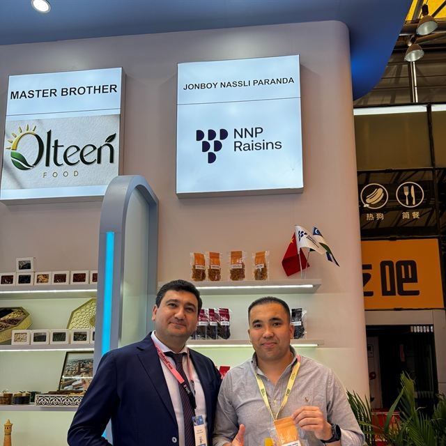 The NNP Raisins stand at SIAL Shanghai 2026, two colleagues in front of the lit fascia sign.