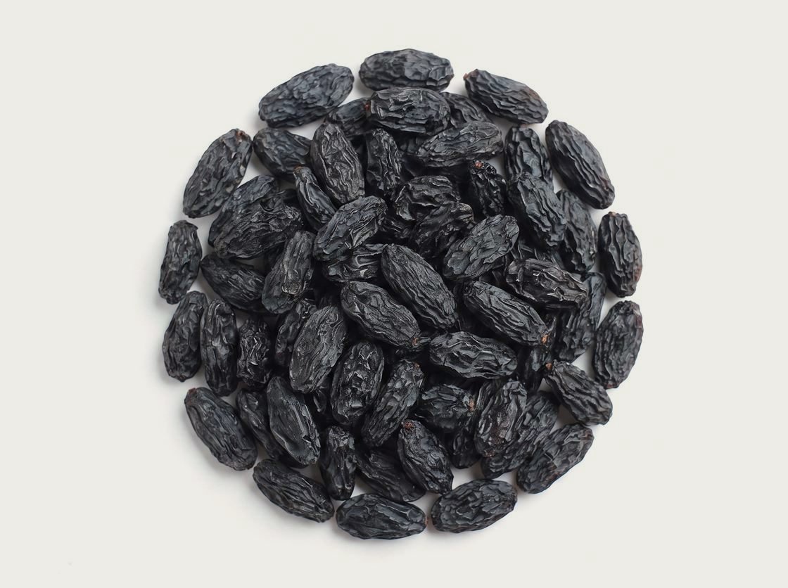 A pile of black Kish Mish raisins, dark and large, photographed from above.