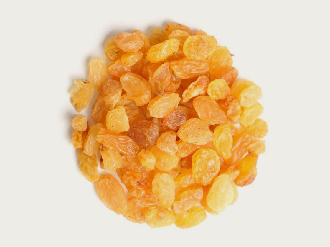 A pile of golden raisins, bright and light in colour, photographed from above.